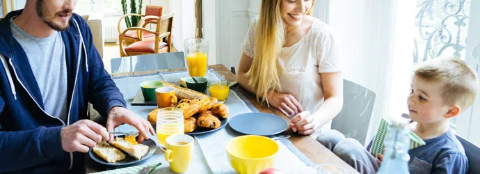 Een gezin van drie zit 's ochtends aan tafel te ontbijten
