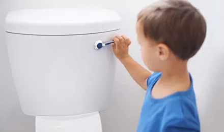 Een kleine jongen spoelt het toilet door