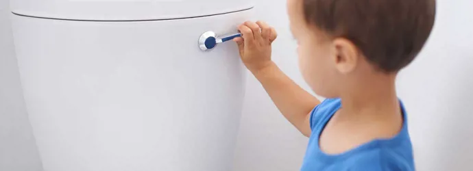 Een kleine jongen spoelt het toilet door