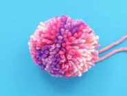 Een wollen pompon gemaakt van garen in verschillende roze tinten.