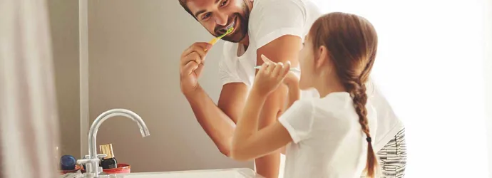 Een man en zijn jonge dochter leren hoe je water kunt besparen, terwijl ze samen tandenpoetsen in een badkamer